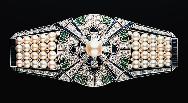 Sash clip ‘Yaguruma’ (Wheels of Arrows) and box, Mikimoto, Japan, 1937, platinum, 18 carat white gold, cultured Akoya pearls, diamonds, sapphires and emeralds. © Mikimoto Pearl Island, Japan