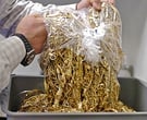 Howard Steinberg, co-owner of Abington Reldan Metals empties a bag of castoff gold bling from a local retail chain store into a tub for weighing. (Clem Murray / Inquirer)